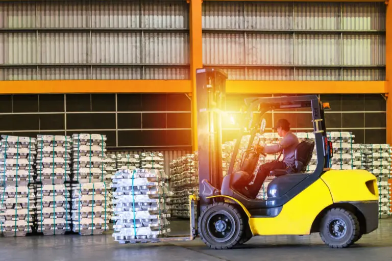 Warehouse forklift truck moving pallet using forks.